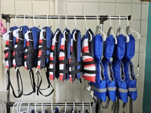 a clothing rack filled with youth and adult life jackets 