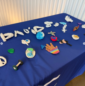 A table with a blue tableloth holds various shapes and sizes of clay art work.